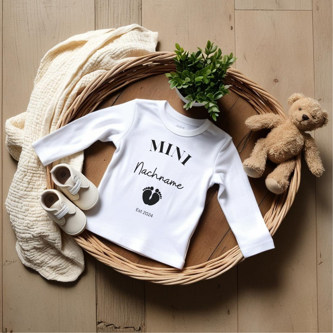 Baby Langarmshirt zur Schwangerschaftsverkündung - Mini Nachname Est. 2025